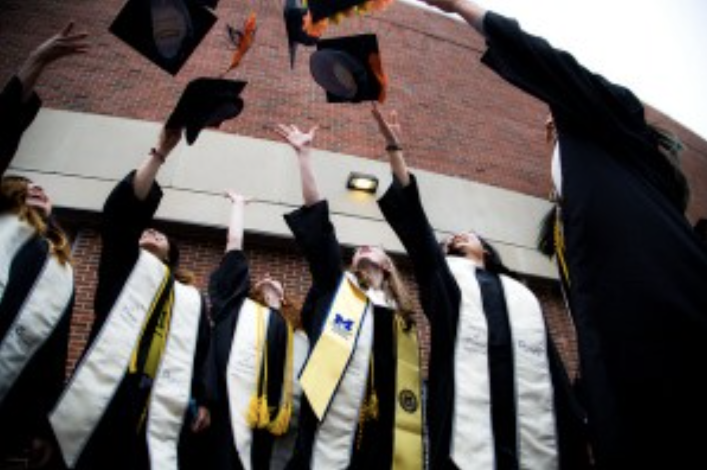 honors degree honors students throwing graduation caps in the air