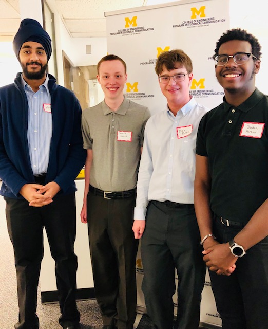 Four smiling young men at a Tech Comm event.