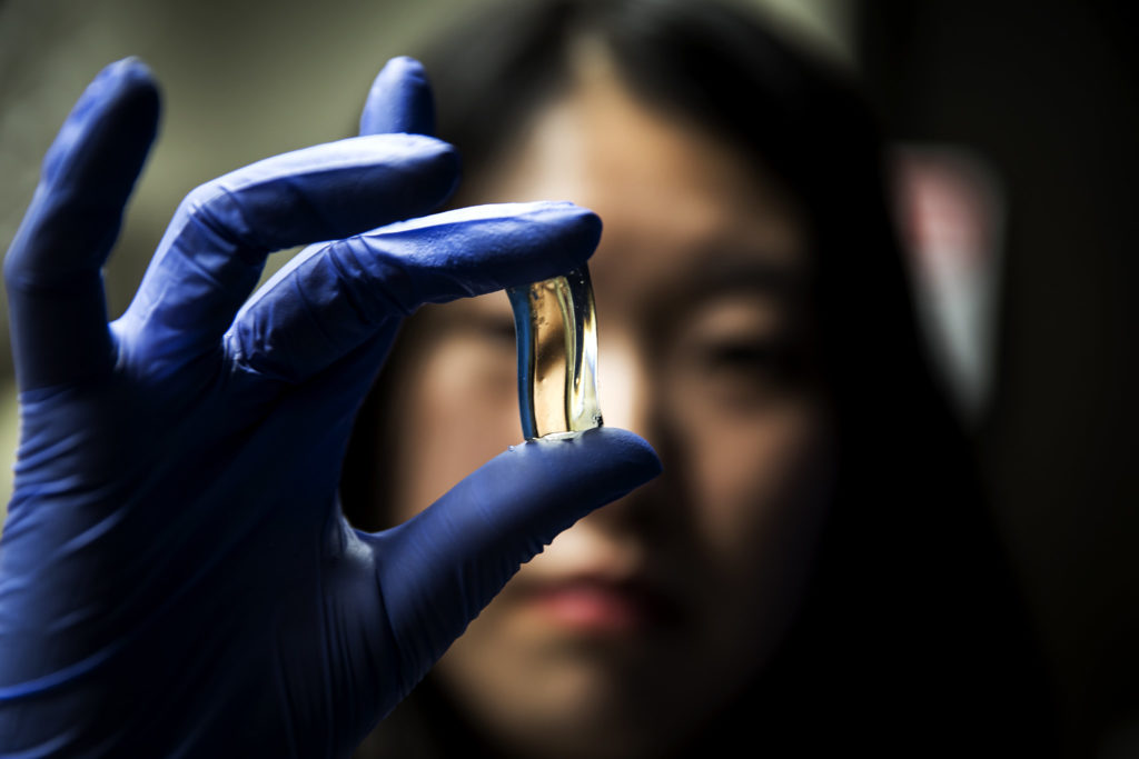 Lab tech out of focus holding up specimen in camera focus